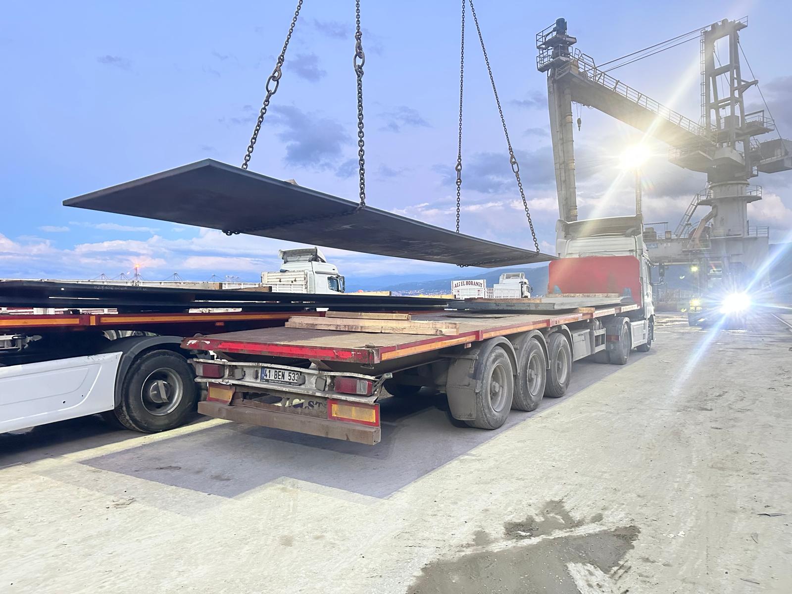 Steel plate loading onto truck at sunset